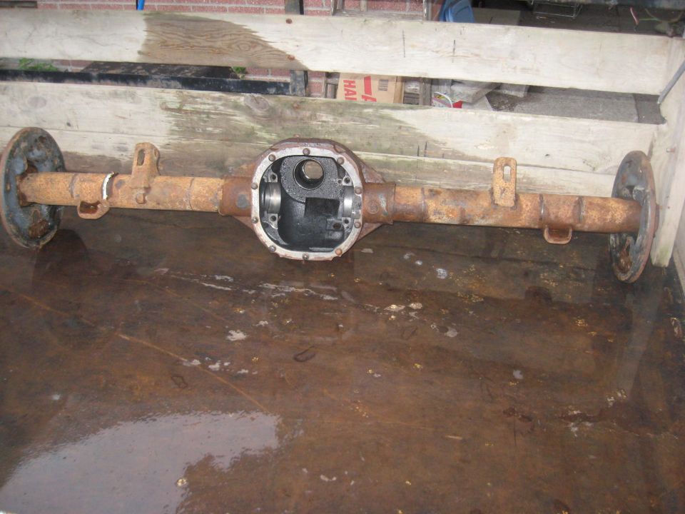Rusty Ford 8.8 inch rear axle assembly with brake drums, viewed from the side