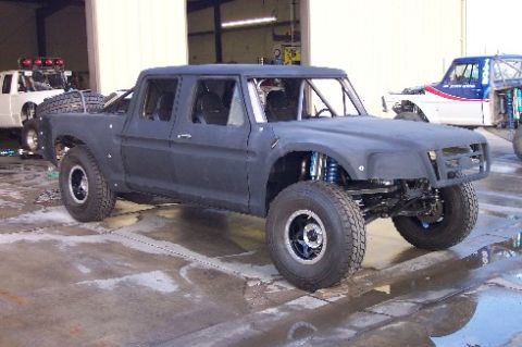 1986 Ford Bronco - A custom-built, four-door off-road truck is shown in a garage, with another vehicle visible behind it.