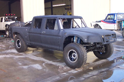 Gray primered prerunner crew cab truck with long-travel coilover front suspension in shop
