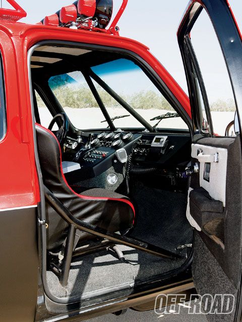 1986 Ford Bronco - The interior of a modified truck features a roll cage, racing seat, and numerous gauges for off-road performance.