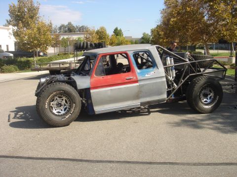 1986 Ford Bronco - This custom-built off-road truck features a roll cage, large tires, and a mix of red and gray body panels.