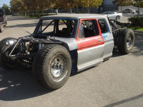 1986 Ford Bronco - Custom off-road truck build with a roll cage and large tires, a mix of red and silver body panels.