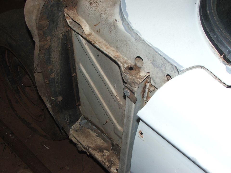 Close-up of rusty car frame and tire well, showing structural components
