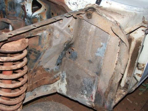1963 Ford Fairlane - Close-up view of heavily rusted car frame and suspension components, showing significant wear and tear.