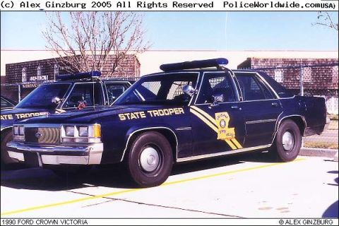1991 Ford LTD Crown Victoria - Two Louisiana State Trooper cars are parked side-by-side in a lot. The car in the foreground has 'STATE TROOPER' written on its door.