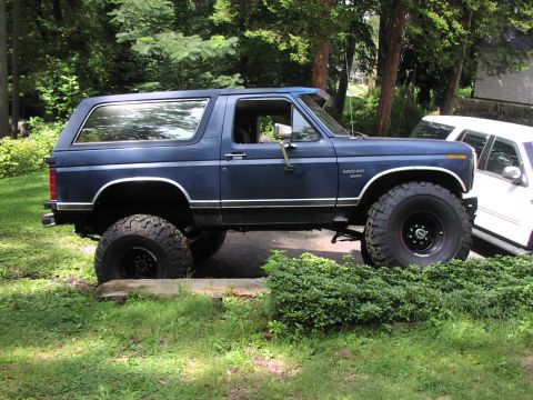 1986 Ford Bronco - Lifted 1986 Ford Bronco with large off-road tires parked outdoors.