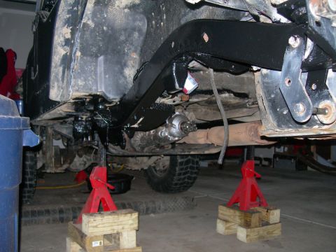 1991 Jeep Wrangler - The undercarriage of a vehicle is shown, highlighting suspension modifications and a D60 swap, with the vehicle supported by jack stands.
