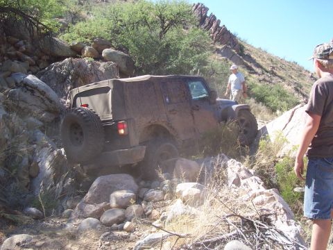 1981 Ford F-150 - A Jeep Wrangler is shown navigating a difficult, rocky terrain on an off-road trail.