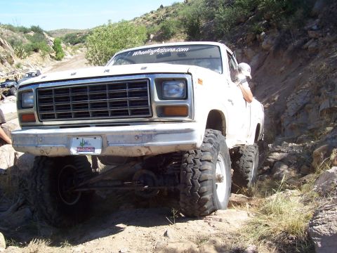 1981 Ford F-150 - Modified Ford pickup truck tackling a challenging off-road course in a rocky, arid landscape.