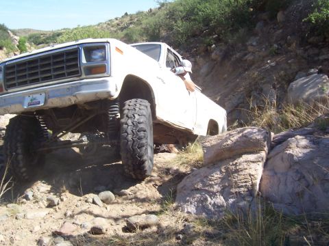 1981 Ford F-150 - A white pickup truck is shown off-roading on a rocky, uphill trail.