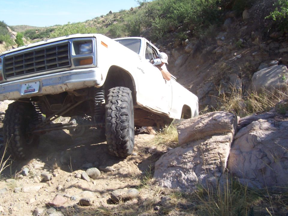 White pickup truck with large tires navigating rocky terrain