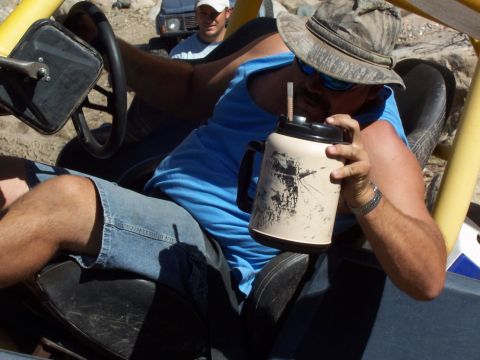1981 Ford F-150 - Driver sips from a large jug inside an off-road buggy, with another vehicle visible behind.