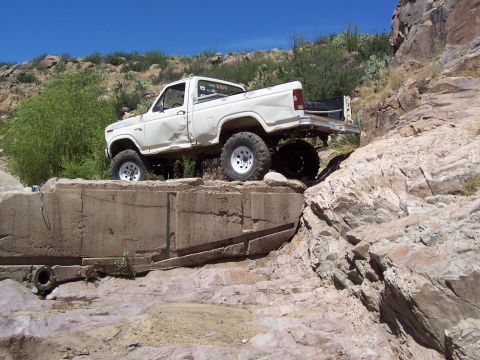 1981 Ford F-150 - White pickup truck with large tires navigating rocky terrain.