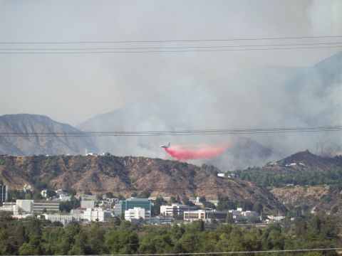 1990 Ford Bronco - A plane drops fire retardant during a wildfire near a suburban area.