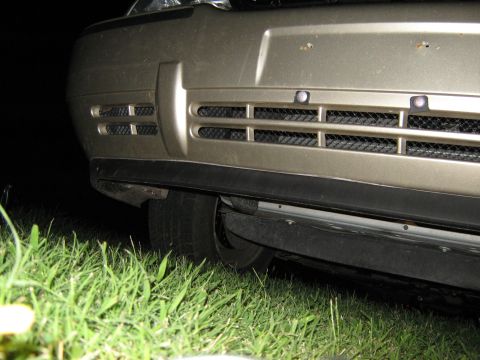 2000 Mercury Grand Marquis - Close-up view of a car's front end, showing the grille and bumper detail against a dark background.