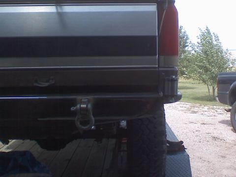1993 Ford Bronco - Close-up view of the rear bumper and tire of an SUV, with another vehicle in the background.