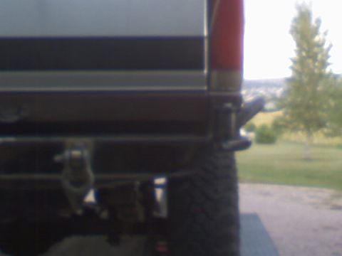 1993 Ford Bronco - A rear view of a vehicle's bumper and tire, with a grassy field in the background.