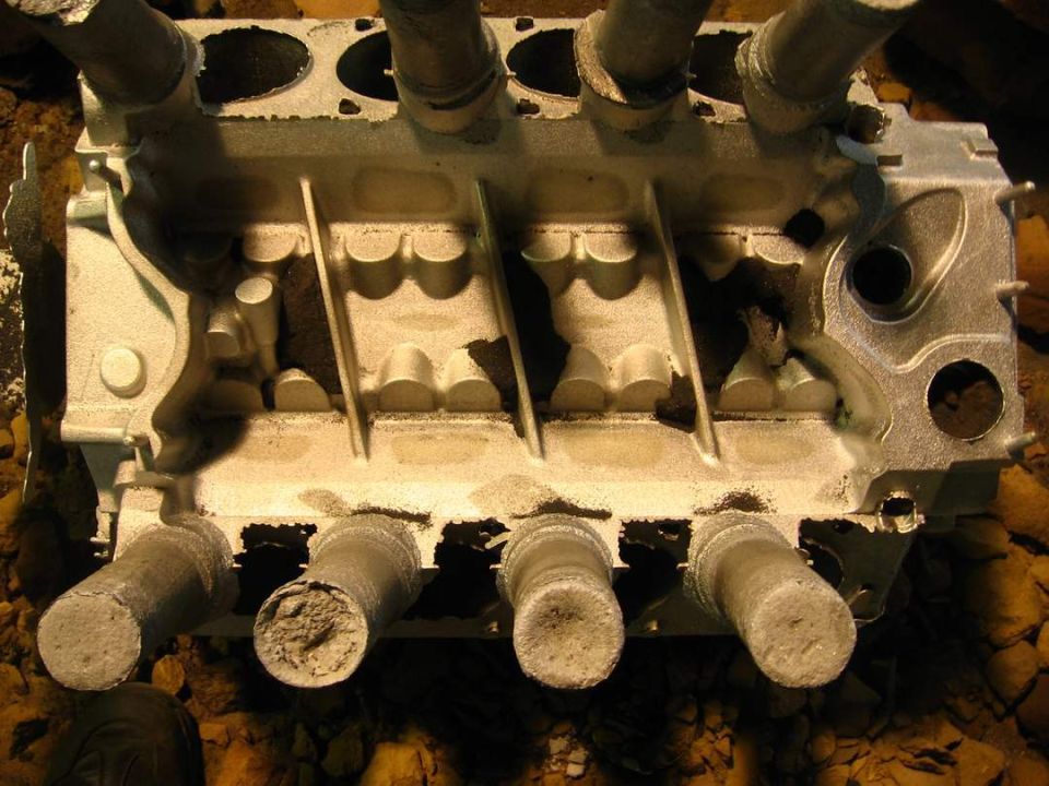 Bare engine cylinder head sitting on the ground