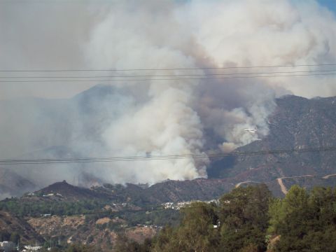 1990 Ford Bronco - A firefighting plane navigates through thick smoke billowing from a wildfire in the mountains.