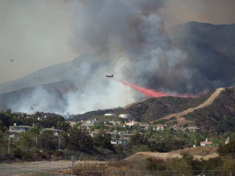 1990 Ford Bronco - Wildfire suppression efforts underway with an air tanker dropping retardant near a residential area.