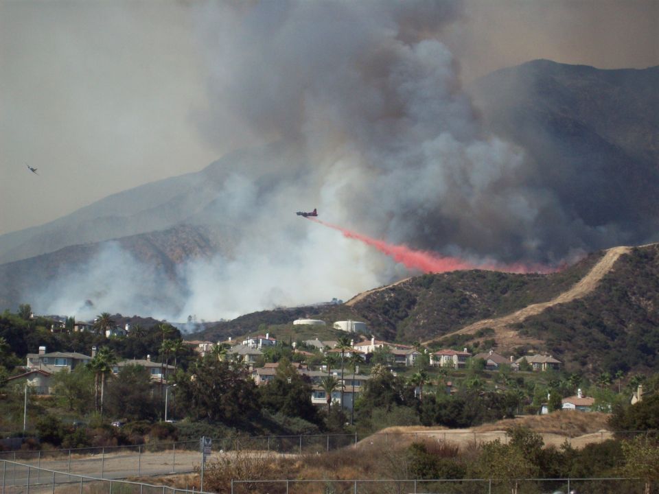 Air tanker drops red retardant on hillside wildfire near homes