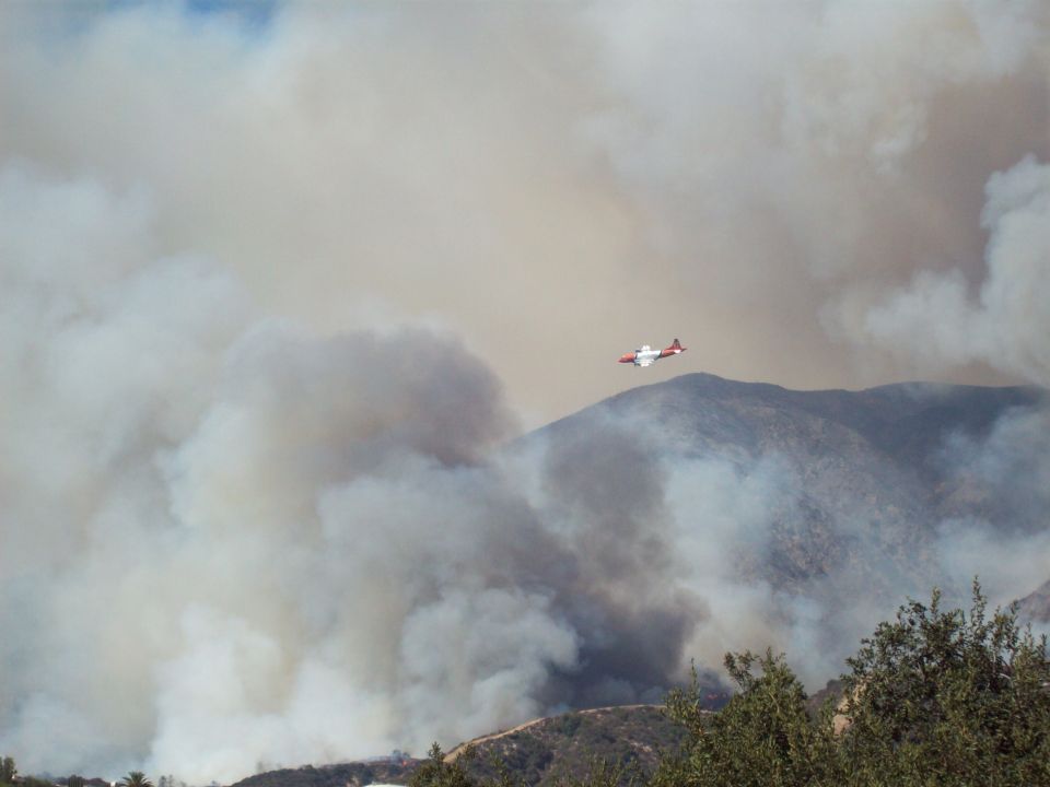 Firefighting air tanker flying over smoky mountains during a wildfire