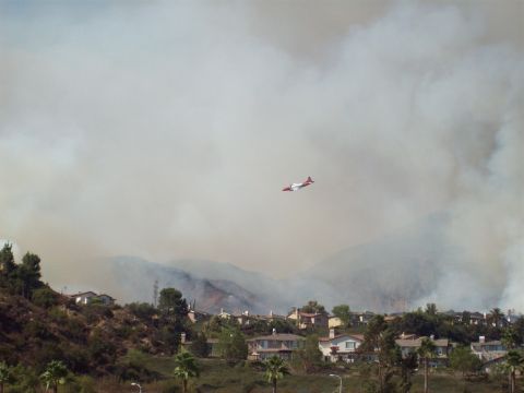 1990 Ford Bronco - An air tanker flies over homes as smoke from a wildfire blankets the sky and hills.