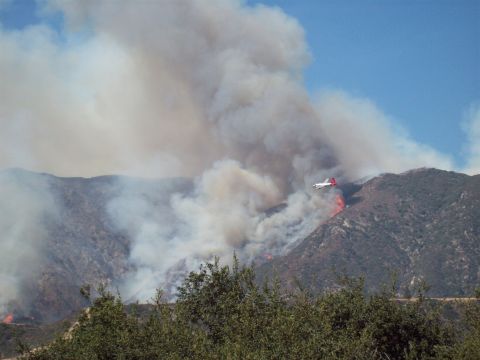 1990 Ford Bronco - An air tanker battles a large wildfire on a dry, mountainous terrain, releasing retardant to control the flames.