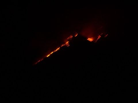 1990 Ford Bronco - A wildfire burns intensely on a dark hillside at night, with smoke visible.