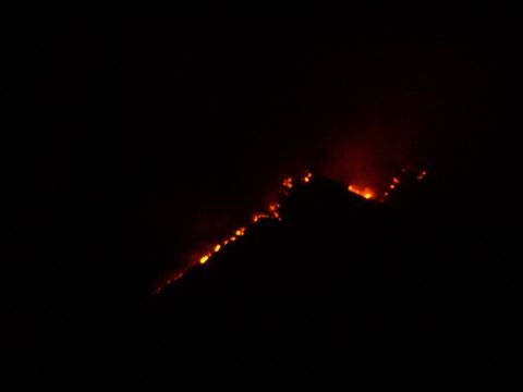1990 Ford Bronco - A wildfire burns across a dark hillside, with flames visible against the night sky.