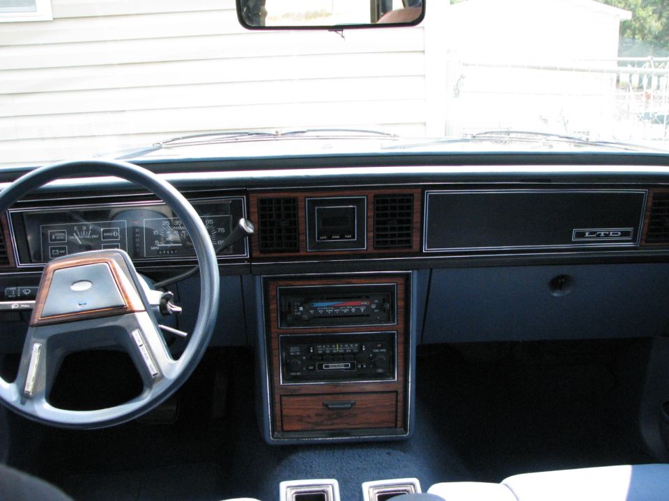 1985 Ford LTD interior with wood trim, blue dashboard, and a four-spoke steering wheel