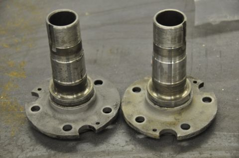 1996 Ford Bronco - A close-up view of two metal spindles, likely automotive parts, resting on a surface.