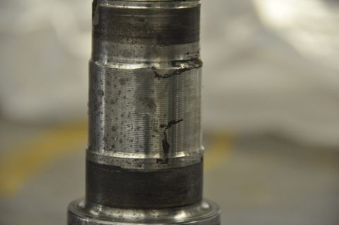 1996 Ford Bronco - A close-up view of a metal spindle shows wear and tear, indicating it is a mechanical part.