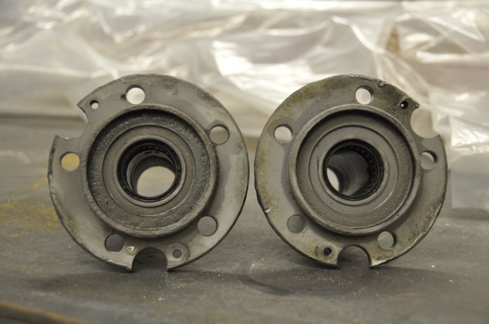 Two metal spindle hubs with bearings, showing wear and dirt