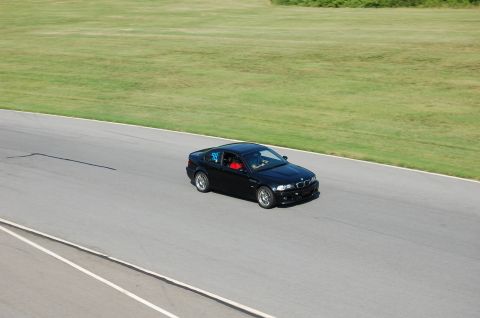 2002 BMW M3 - A black 2002 BMW M3 with racing number 98 on the door navigates a turn on a sunny day at the racetrack.