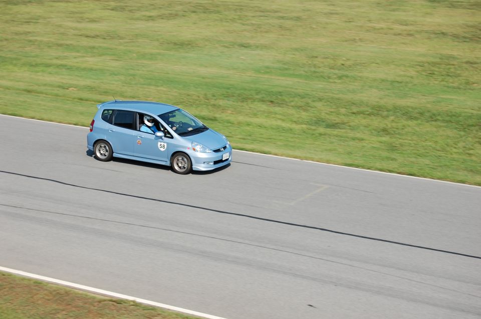 Blue Honda Fit with number 58 on door driving on a race track