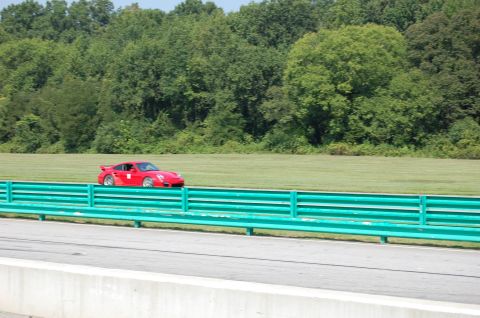 2002 BMW M3 - Red Porsche 911 on a race track with trees in the background.
