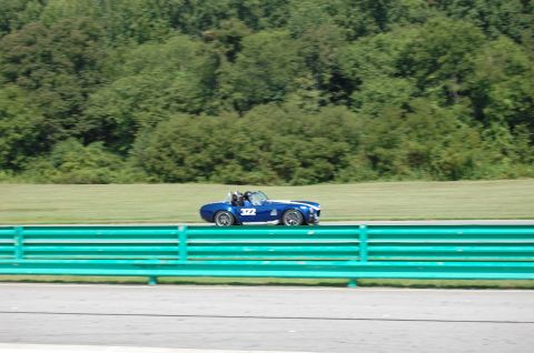 2002 BMW M3 - Blue convertible race car with number 322 on track, trees in background.