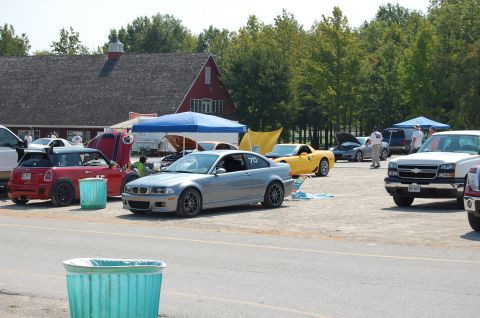 2002 BMW M3 - A silver BMW coupe with racing numbers is parked on a gravel lot near a red barn and trees.