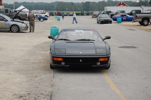2002 BMW M3 - A black Ferrari 355 is parked on a track, displaying the number 355 on its windshield.