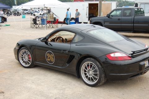 2002 BMW M3 - Black Porsche Cayman with racing number 26 on the door, parked at an outdoor event.