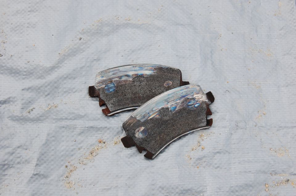 Two worn brake pads on a white cloth. Supermotors.net logo visible