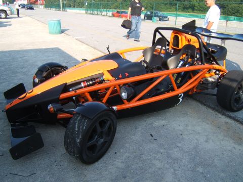 2002 BMW M3 - Ariel Atom race car with exposed suspension and roll cage is parked on pavement.