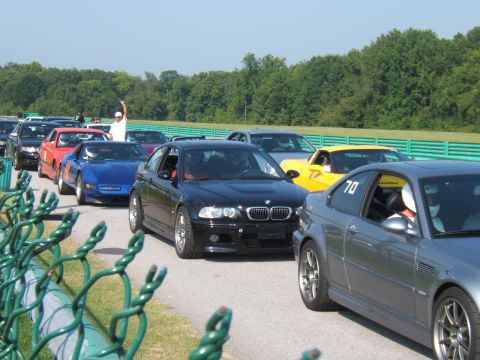 2002 BMW M3 - Multiple cars line up on a race track, with a black BMW M3 in the foreground.