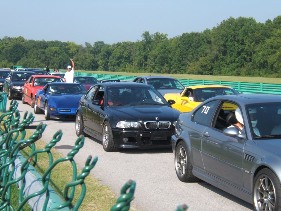 Black BMW M3 with racing stripes, front view, on a track