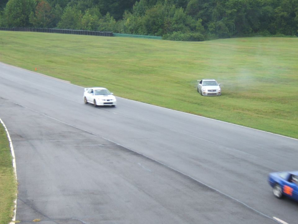 White WRX on track as silver CTS-V sits off course in the grass