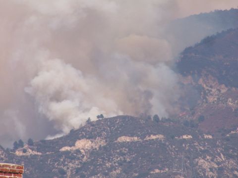 1990 Ford Bronco - Thick smoke from a wildfire drifts over a mountainous, brush-covered landscape.