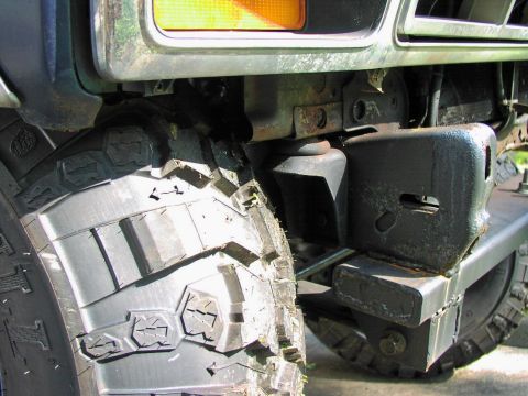1986 Ford Bronco - A close-up view of a vehicle's front tire and aftermarket bumper, showing off-road modifications.