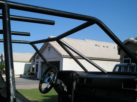 1986 Toyota Hilux - Vehicle interior shows a custom roll cage and dashboard, with houses in the background.