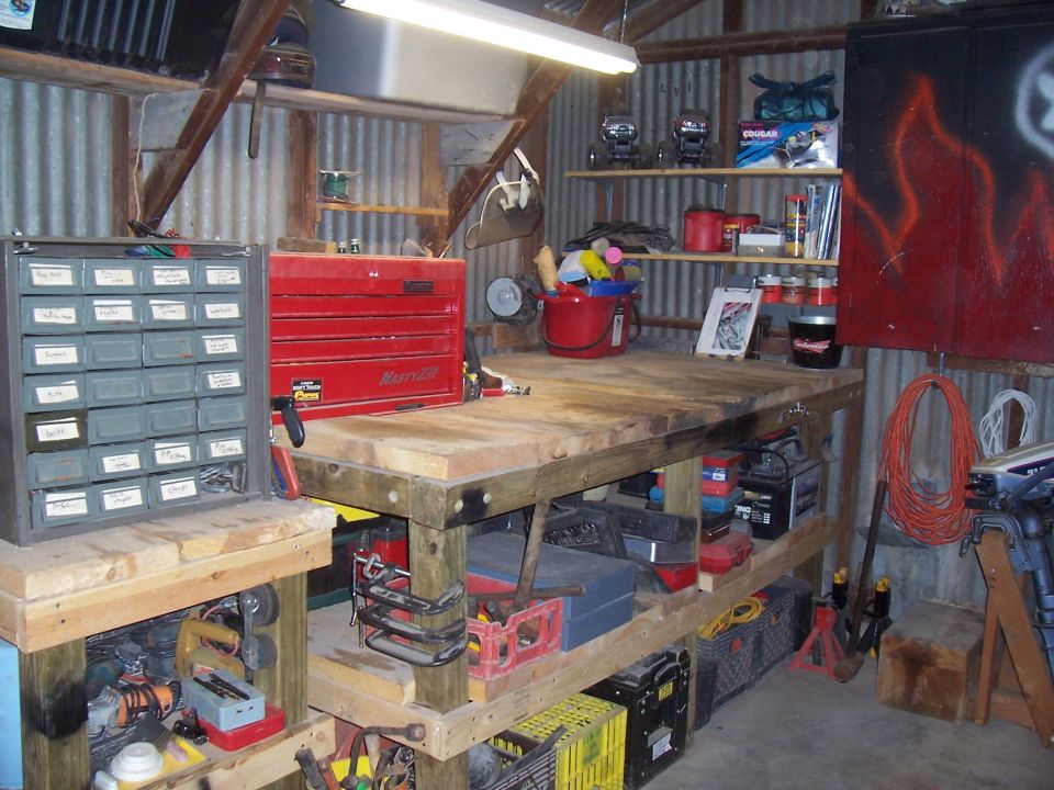 Workbench with red tool chest, grey parts organizer, and various tools in a workshop